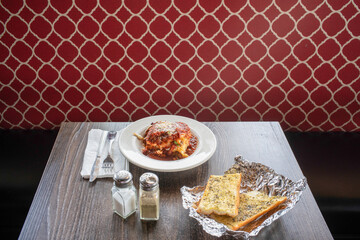 Bowl of lasagna and garlic bread on table patterned booth