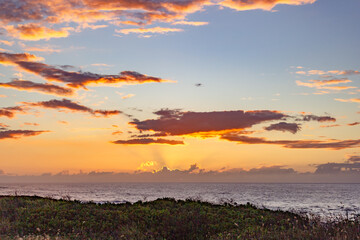 Vibrant sunset with dramatic clouds over the ocean in Hawaii.