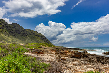 Dramatic coastal landscape with mountains and rocky shore in Hawaii.