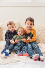 Smiling brothers hugging and smiling while sitting on bed