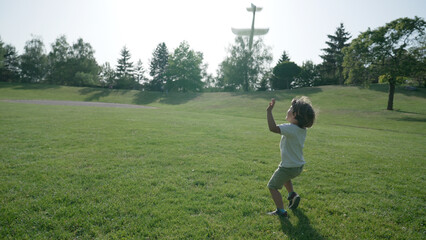 Young Boy Playfully Running with a Toy Airplane in a Lush Park