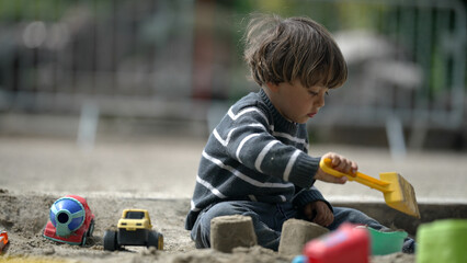 Young Boy Playing in Sandpit with Toys, Digging with Yellow Shovel