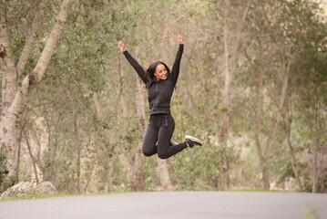 Excited women running with her hands in the air in the woods