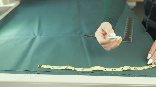 Female tailor marking rough edge of fabric