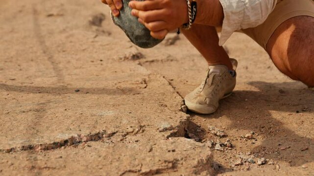 Tourist trying out ancient Egyptian method of granite stone cracking at Unfinished Obelisk quarry in Aswan.