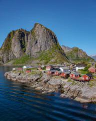 A scenic view of a small village in Norway, with red cottages nestled on the rocky coastline...