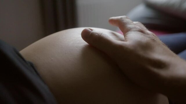 Hand stroking baby belly of mother and squeezing