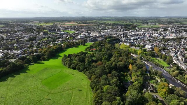 Kilkenny Castle, County Kilkenny, Ireland, September 2023. Drone at a higher angle orbits the grounds with St Canice's Cathedral and Saint Mary's Cathedral in the distance.