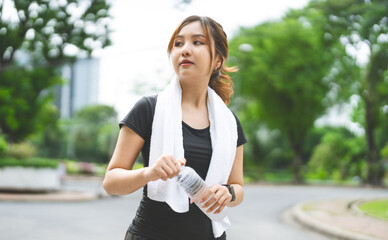 Asian woman exercise and fitness at outdoor with pet bottle drinking water and towel