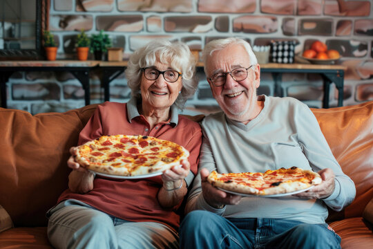 Portrait of  happy senior couple eating pizza and enjoying evening at home - Powered by Adobe