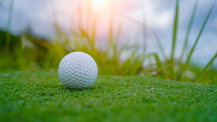 Golf ball on green grass in the evening golf course with sunshine background.