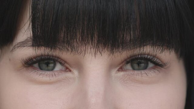 A close up portrait of young beautiful woman with green eyes, smiling looking at camera. beautiful brunette girl with short bang is opening and blinking her eyes. natural beauty