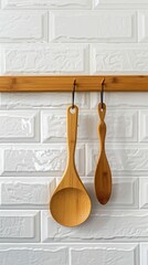 a modern kitchen space featuring wooden utensils and aprons neatly arranged on a hanger, set against a pristine white tile backdrop, showcasing eco-friendly and sustainable living aesthetics.