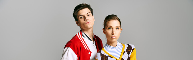 Stylish male and female students strike a pose in front of a neutral background.