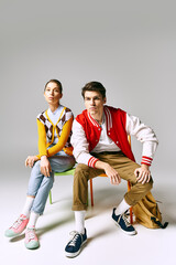 Naklejka premium A man and a woman, attractive and casually dressed, pose on a chair in a college classroom.