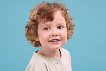 Portrait of cute little boy on light blue background