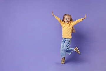 Obraz premium Cute little girl dancing on purple background, space for text