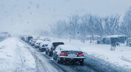 Snow covered cars on a highway during a snow storm with bad road conditions