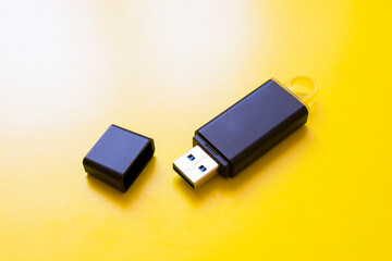 Flash drive with a cover on a yellow background close-up.
