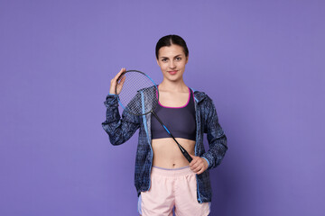 Young woman with badminton racket on purple background