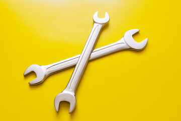 Two open-end wrenches on a yellow background.
