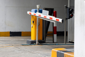 A red and white traffic light is on the side of a road. automatic barrier bar.