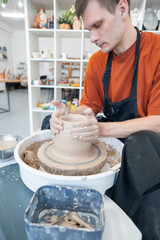 A potter works on a potter's wheel to smooth the surface of a vase.