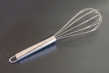 The whisk lies on a black background.