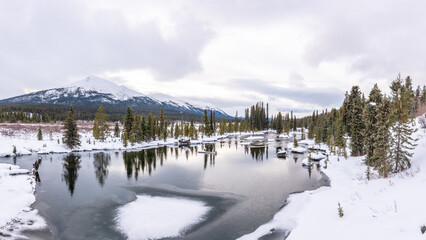 Landscape view in northern Canada during winter time with creek running through Boreal Forest area. Taken near Atlin, British Columbia. 