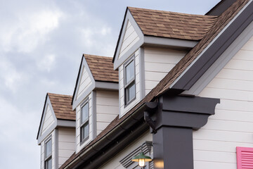 A house with a slanted roof and a window on the top. garret house with roof shingle.