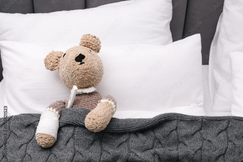 Canvas Prints Toy cute bear with bandage and thermometer under blanket in bed