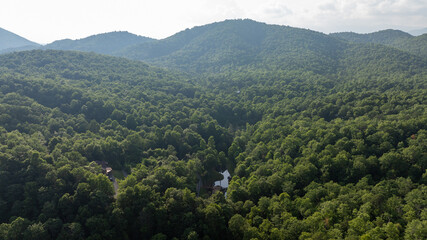 Naklejka premium Aerial view of lush green mountains with winding roads and scattered houses, located in Black Mountain, North Carolina.