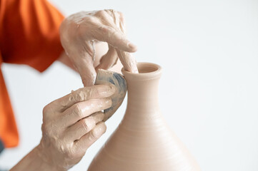 A potter works with a tool on a potter's wheel leveling the surface of a vase. 