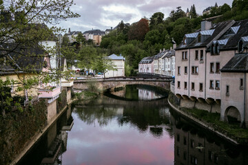 Obraz premium Sunset in the old european city the capital of Grand Duchy of Luxembourg. Burgundy red sky reflects in the water of Alzette river in Grund quarter Pfaffenthal district of Old Town in Luxembourg