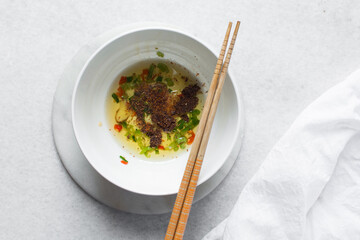 Overhead view of Slices of red green chilli and oil in a white ceramic bowl, top view of spices chili peppers chopsticks in a white bowl, process of making chili oil