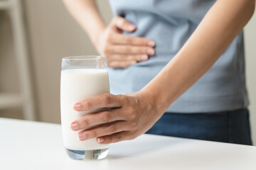 lactose intolerance concept. Woman holding a glass of milk and having a stomachache.
