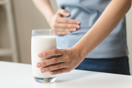 lactose intolerance concept. Woman holding a glass of milk and having a stomachache.