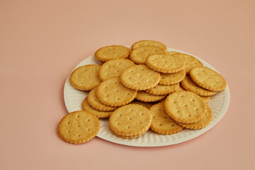 Saltine crackers close-up on plate on pink background, cookies on paper disposable plate, freshly baked cookies