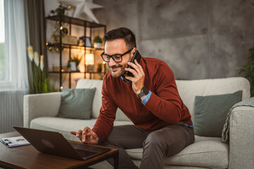 Fototapeta premium Adult businessman work from home and talk on mobile phone