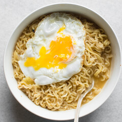 overhead view of a bowl of ramen with a fried egg, top view of a runny egg with noodles