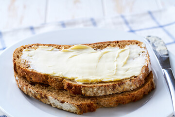 slices of rye wheat bread with butter, on a light kitchen table.