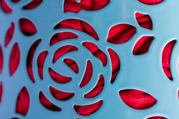 Close up of blue floral shaped with holes texture and red clothes inside as background