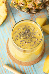 Pineapple and banana smoothie with chia seeds on wooden table. Top view. Healthy tropical blended drink, vegan detox juice with fresh organic fruit.