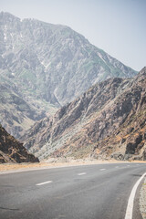 Automobile asphalt road in the mountains in the valley between rocky mountains, Pamir Highway in Tajikistan