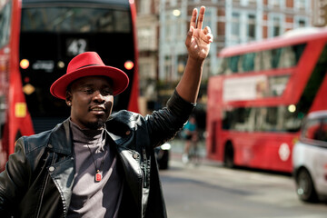 A man is hailing for a cab in a busy London street.