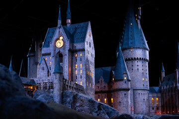 Fototapeta premium JAPAN - Nov 13, 2023: Closeup night view of Hogwarts Castle's clock tower illuminated beautifully highlighting its magical architecture at Warner Bros. Studio Tour Tokyo, The Making of Harry Potter