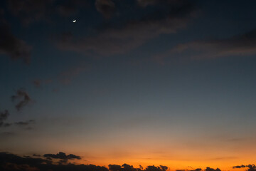 Crescent moon shines above a vibrant sunset horizon gradient tone capturing the serene transition from day to night