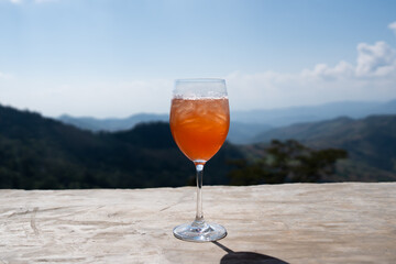 Refreshing punch iced drink in a wine glass set against a stunning peaceful natural scenic mountain view on a sunny day in the summer