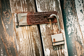 rusted metal padlock on a wooden shed door