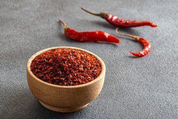 Red pepper flakes.Red chili peppers in wooden bowl on gray background.Dried chili peppers